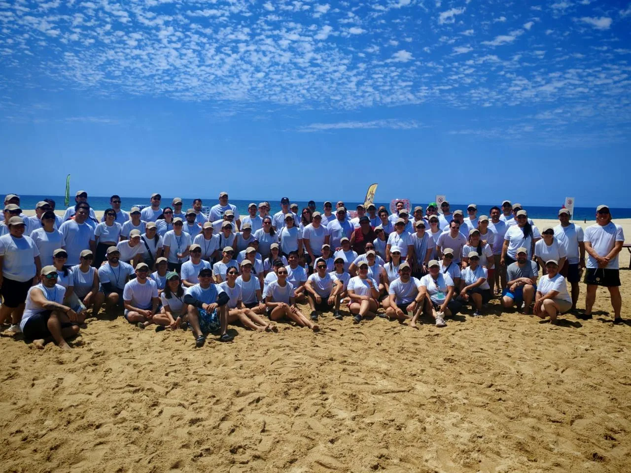 Grupo corporativo completo en la playa durante un evento de team building de TEAMS en Los Cabos
